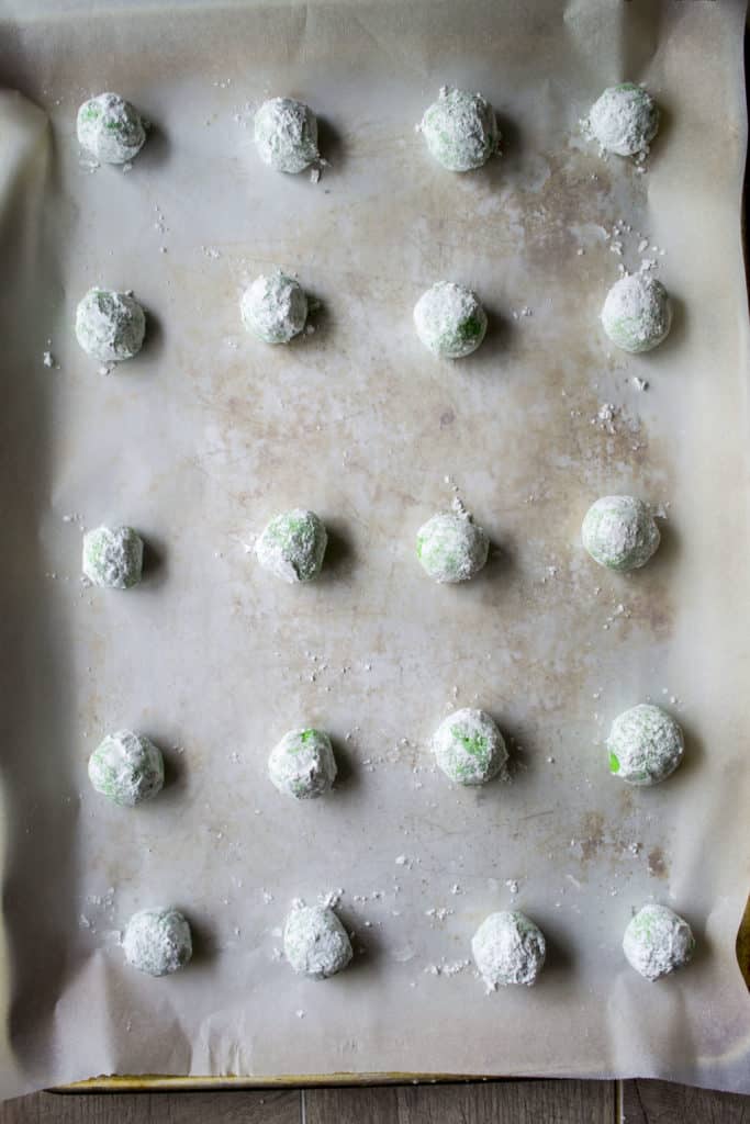 Green Christmas Crinkle Cookies balled up and on a baking sheet
