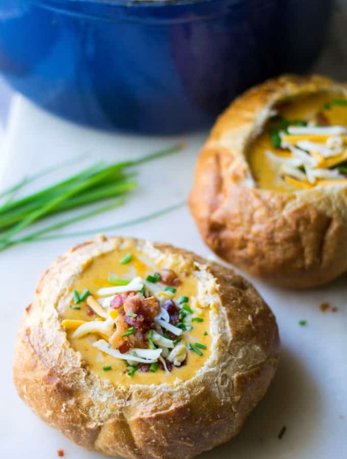 Beer Cheese Soup in a bread bowl garnished with bacon and green onions
