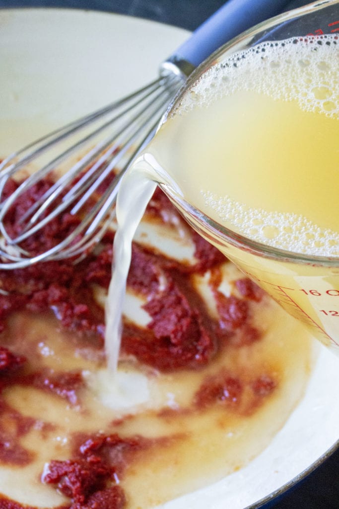 chicken stock being poured into pan