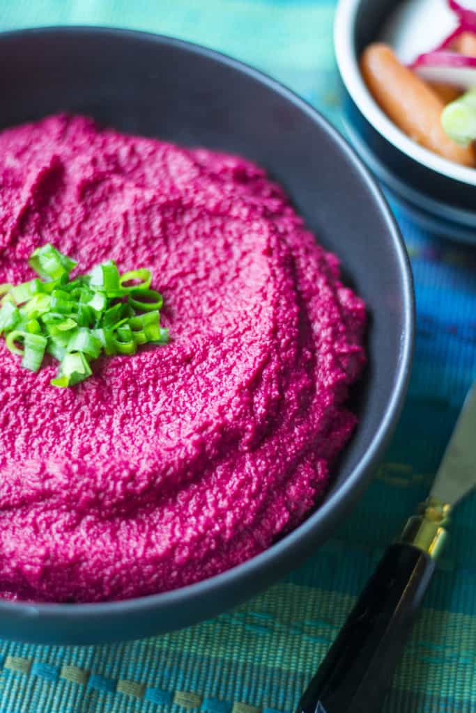 Roasted Beet Hummus is an easy, healthy Game Day recipe made with roasted beets, chickpeas, fresh lemon and a bite of garlic. Bright vibrant pink, Roasted Beet Hummus is creamy smooth hummas perfect to serve up with pita chips and yes, it really is better than store-bought!