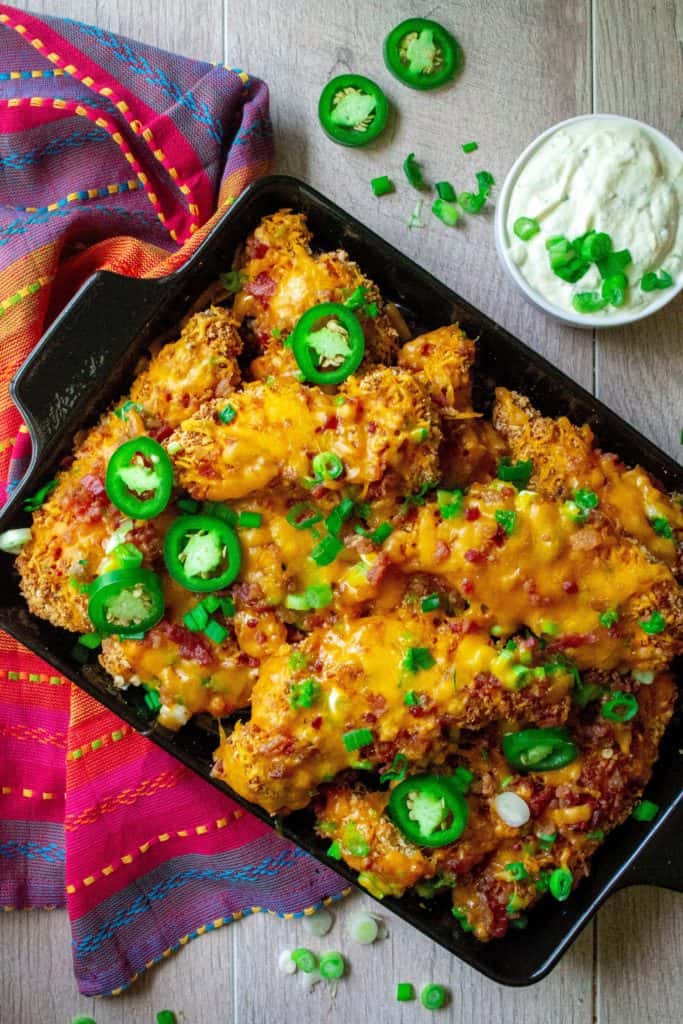 Loaded Chicken Tender Nachos are a delicious fun twist on plain ol' chicken tenders. Loaded with melted cheddar cheese, crispy bacon, green onions and spicy jalapeno, these Loaded Chicken Tender Nachos are easy, quick and the best comfort food! | A Wicked Whisk
