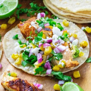 Mexican Street Corn Chicken Tacos bring together your love of Mexcian steet food elote and spicy chicken tacos.  Made with fresh roasted corn, cilantro, lime, seasoned chicken and a creamy chipotle sauce, these Mexican Street Corn Chicken Tacos will have you begging for more!