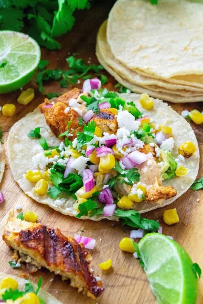 Mexican Street Corn Chicken Tacos bring together your love of Mexcian steet food elote and spicy chicken tacos.  Made with fresh roasted corn, cilantro, lime, seasoned chicken and a creamy chipotle sauce, these Mexican Street Corn Chicken Tacos will have you begging for more!
