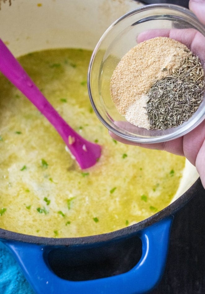 adding spices and herbs to soup pot