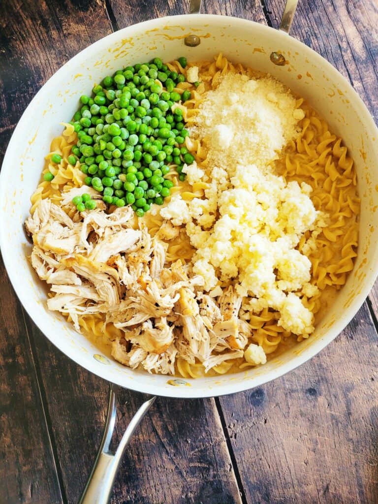 adding cheese, chicken and peas to chicken casserole