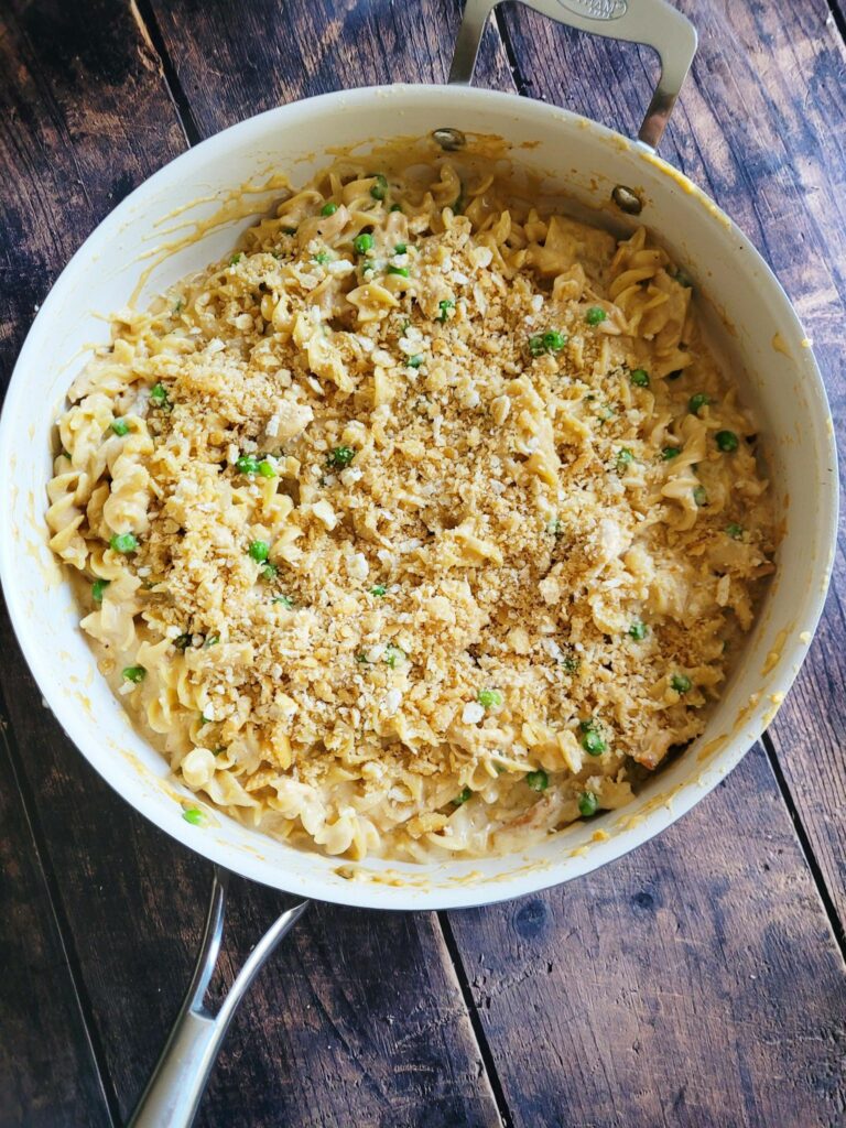 adding buttery cracker topping to a noodle casserole