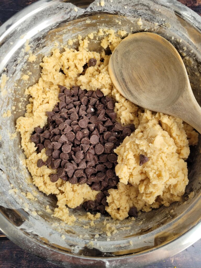 Mixing bowl filled with cookie dough, loaded with chocolate chunks.