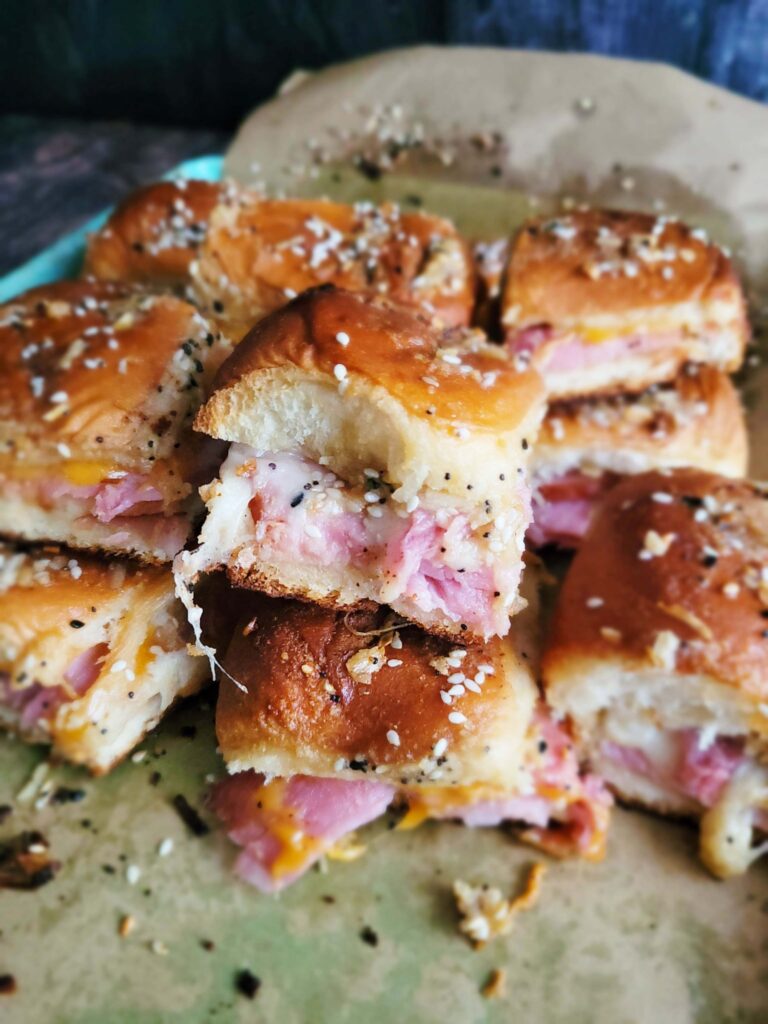 Close-up of ham layered with melted Swiss cheese inside fluffy Hawaiian rolls.