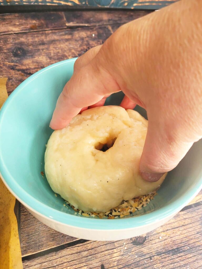 dipping sourdough bagel in bagel toppings