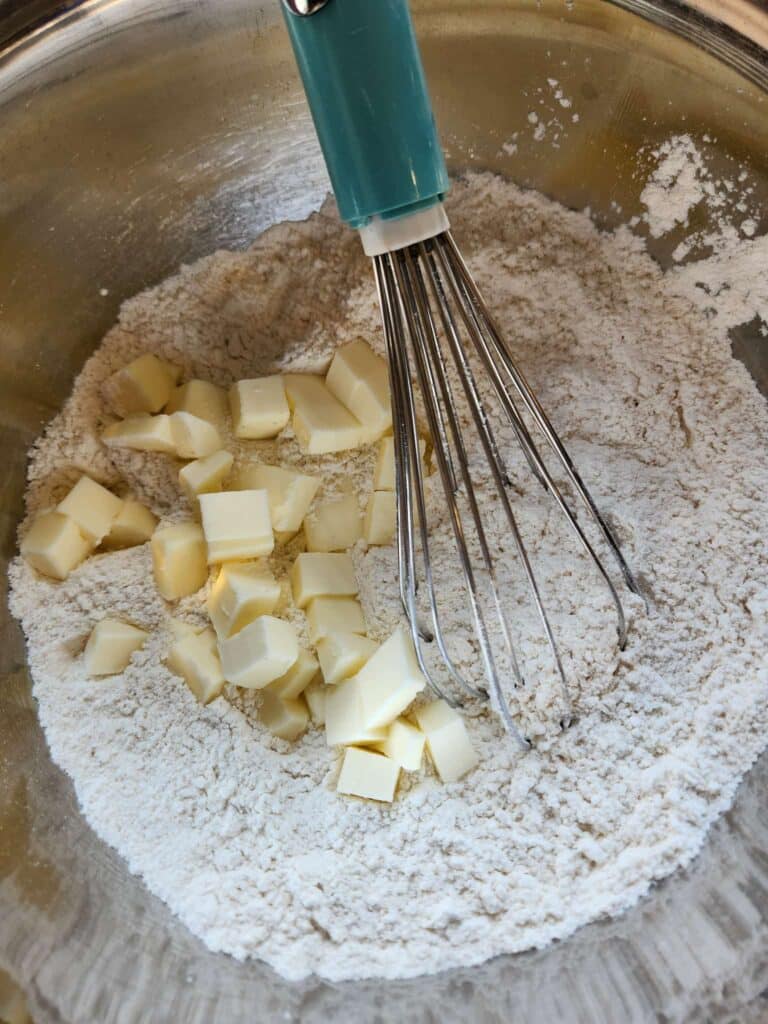 adding cut butter to biscuit dough