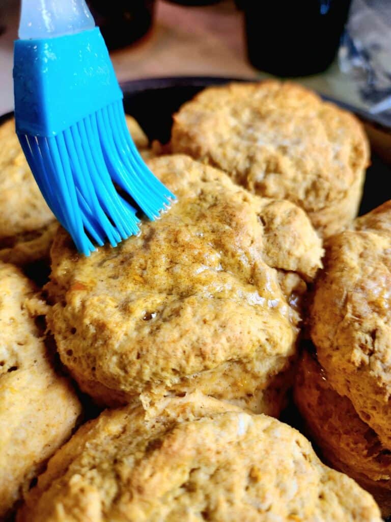 brushing butter on a sweet potato biscuit