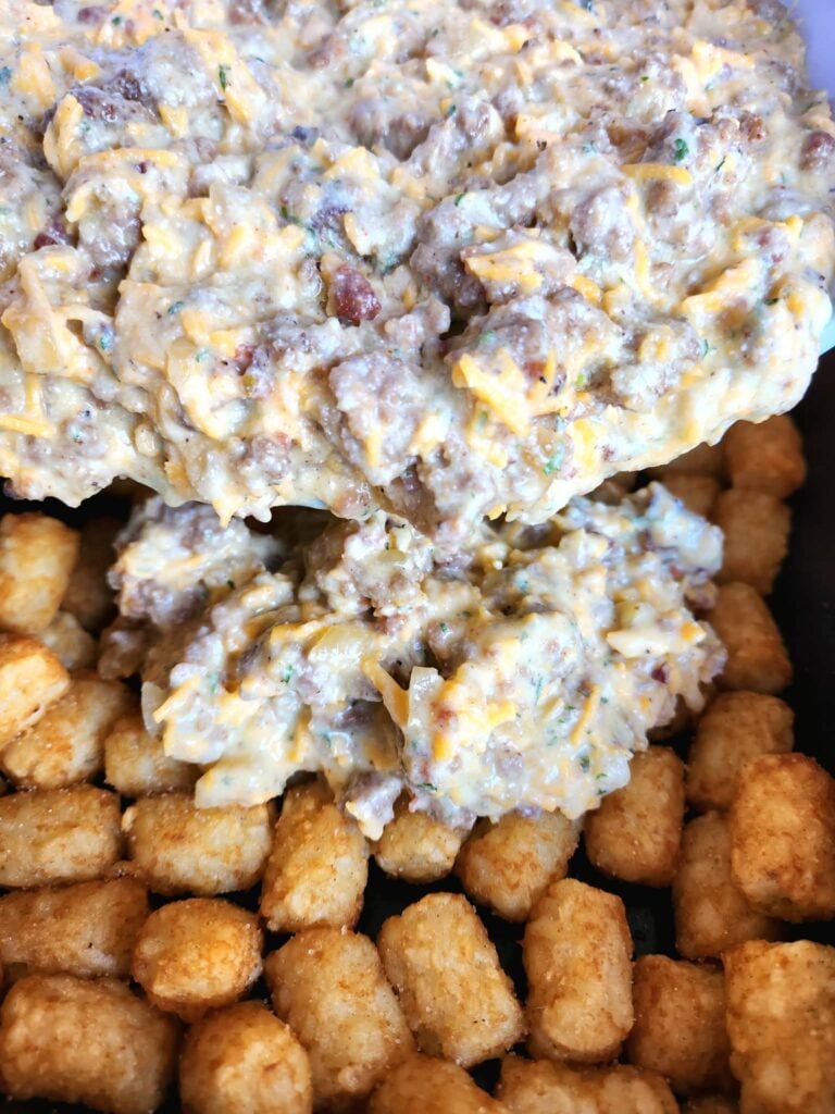 Smooth egg-ricotta-sausage mixture being poured evenly over pre-baked tater tots in the baking dish.
