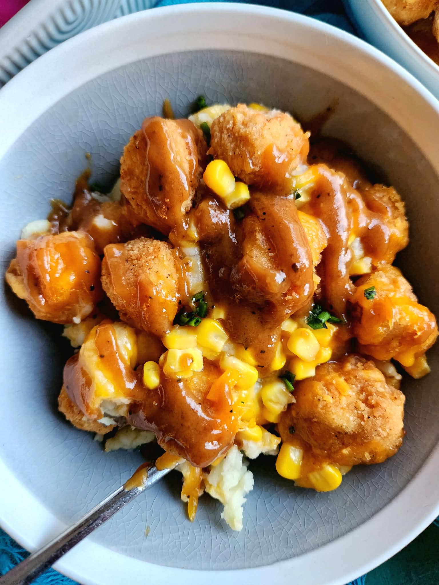 Homemade KFC Famous Bowl with layers of mashed potatoes, gravy, corn, crispy chicken, and melted cheddar cheese in a cozy bowl