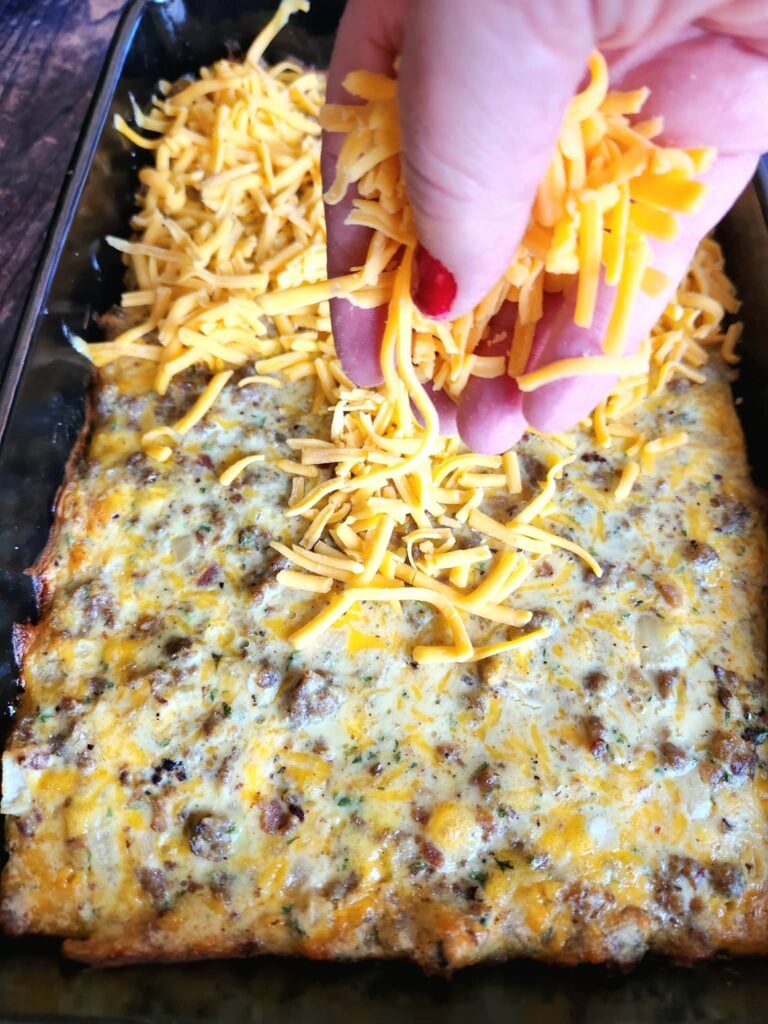 adding reserved cheddar cheese to sausage breakfast bake