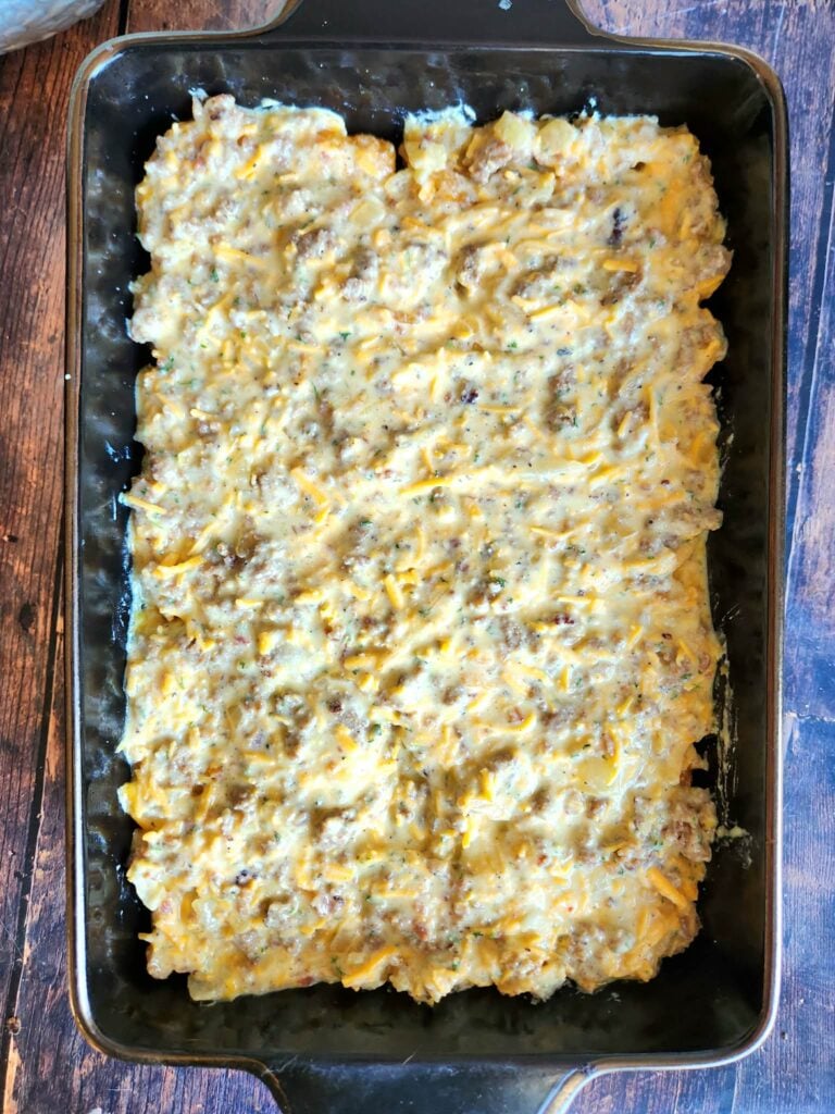 egg-ricotta-sausage mixture being poured evenly over pre-baked tater tots in the baking dish.