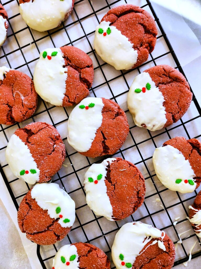 Holiday red velvet cookies decorated with tiny holly design on white chocolate for Christmas.