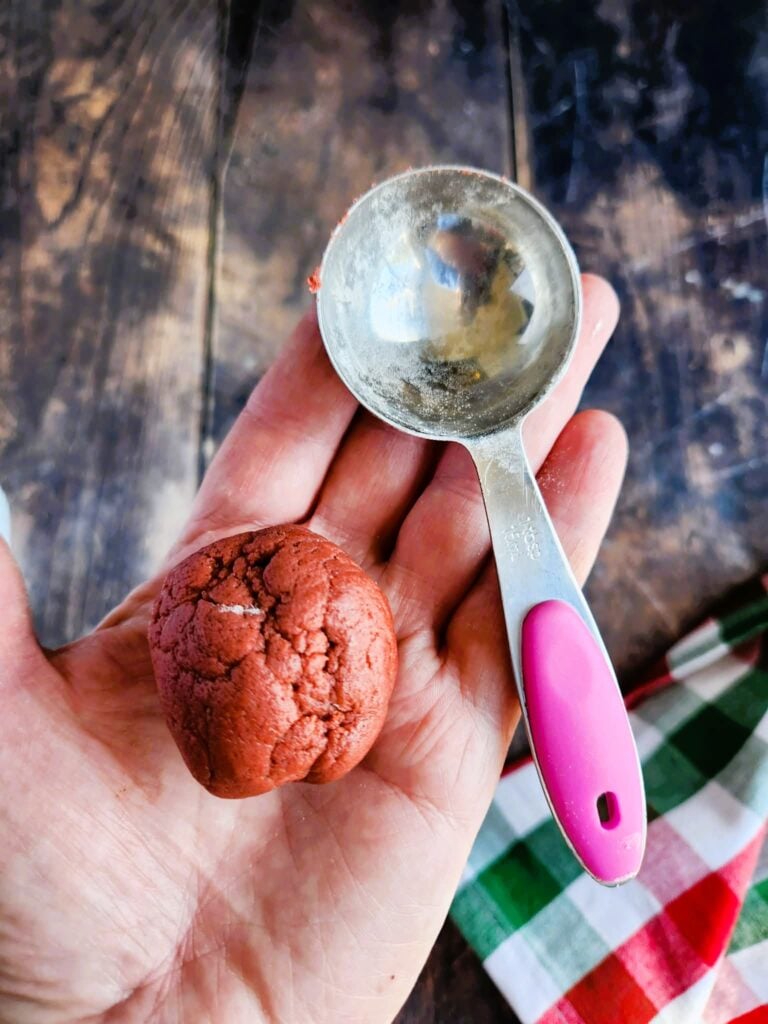 measuring out large balls of red cookie dough