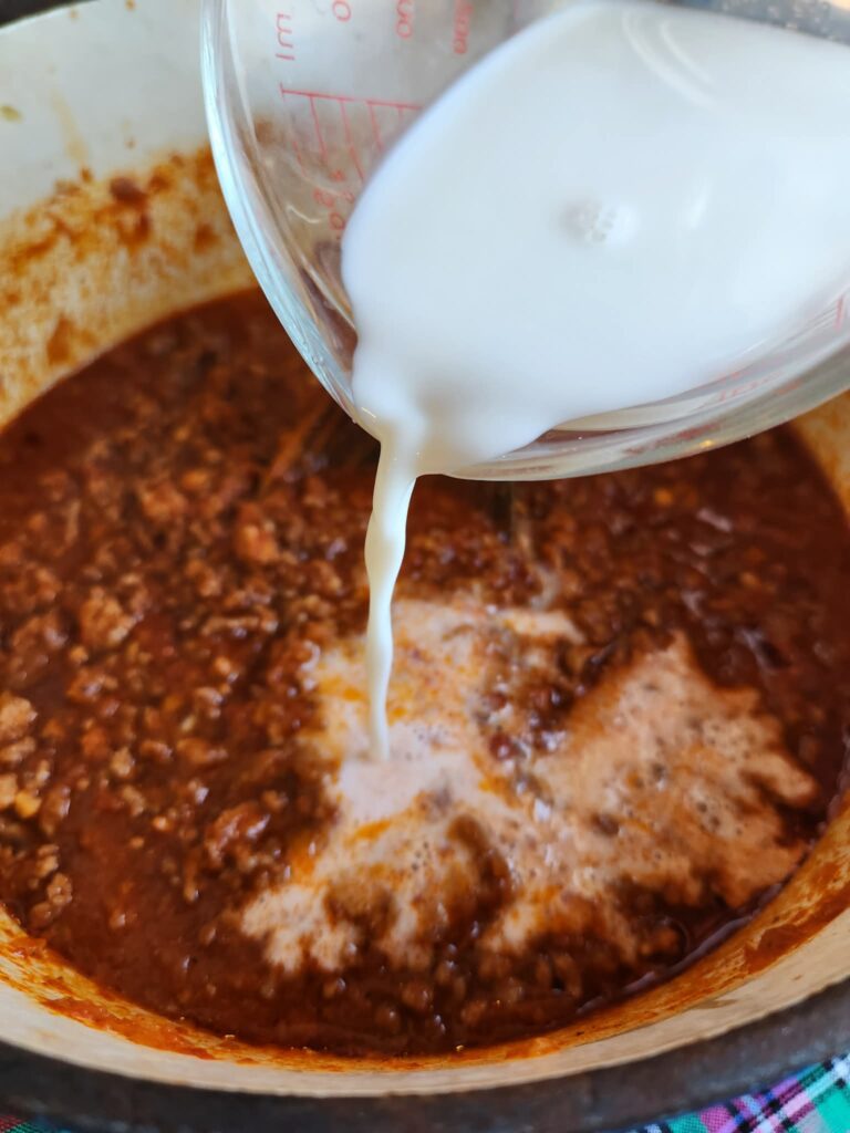 adding milk to the bolognese sauce