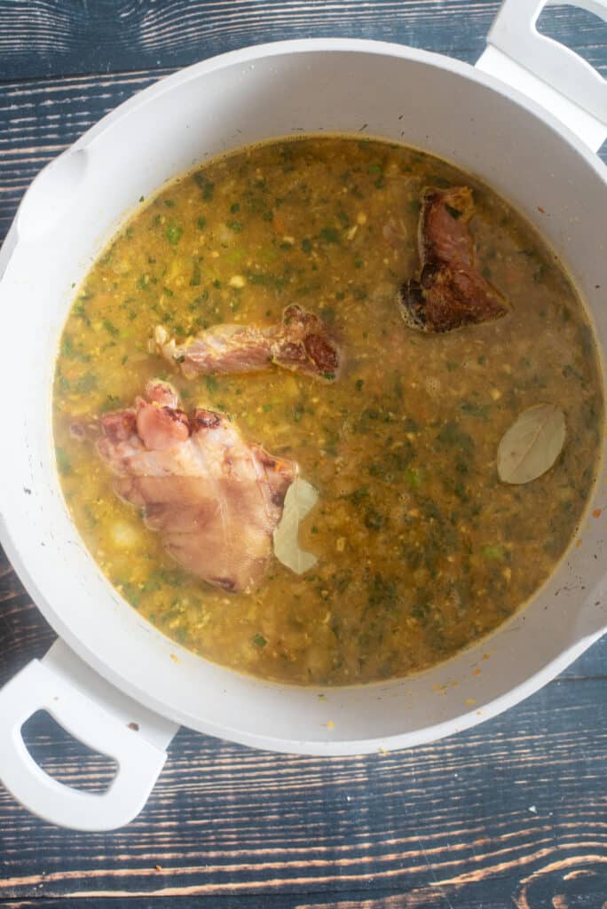 adding broth and bay leaves to create the soup