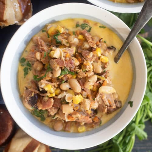 Creamy ham white bean soup in rustic bowl with parsley garnish and crusty bread