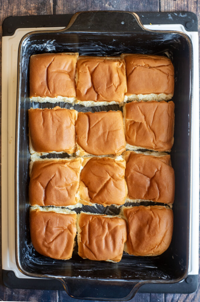 Mini potato rolls arranged snugly in a greased 13x9-inch baking pan before baking.