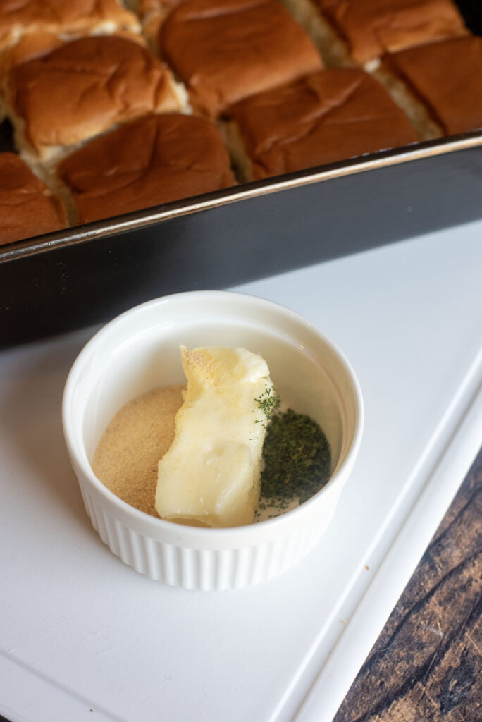 Close-up of garlic butter, garlic powder, salt, and parsley being mixed in a microwave-safe bowl.