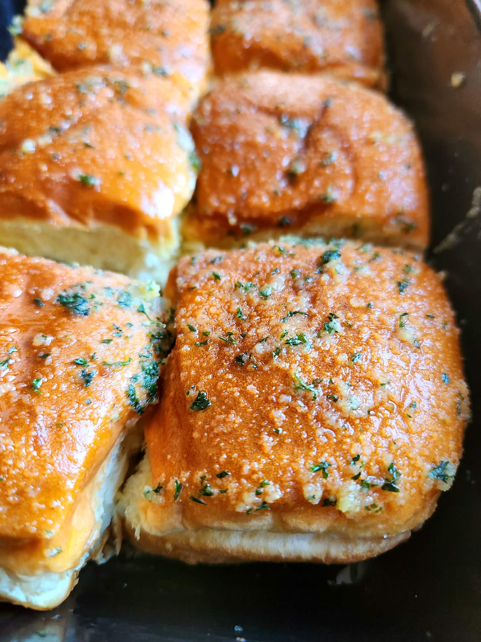 Fully baked 10 minute garlic dinner rolls in baking dish, golden and glossy.