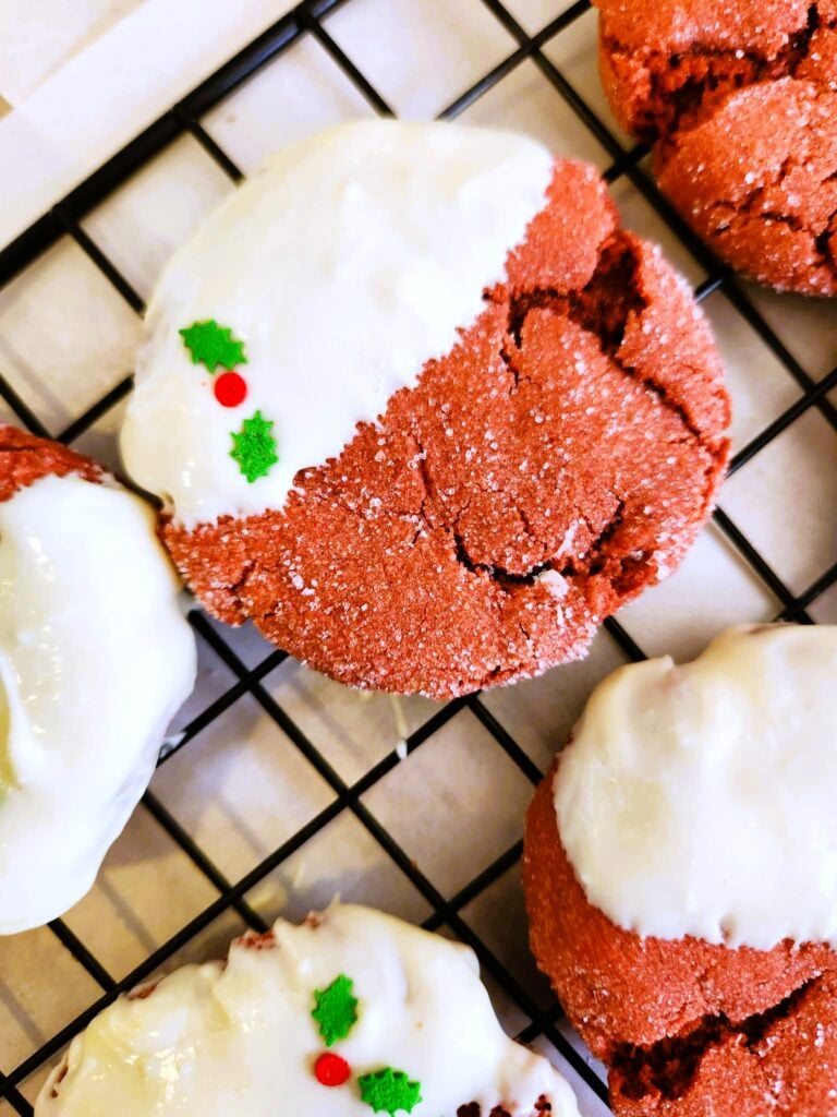 Holiday red velvet cookies decorated with tiny holly design on white chocolate for Christmas.
