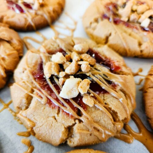 Soft peanut butter and jelly cookies with extra jam, peanut butter drizzle, and chopped peanuts