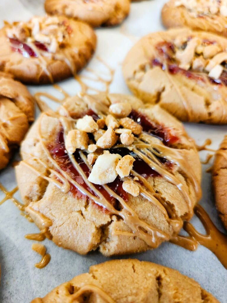 Soft peanut butter and jelly cookies with extra jam, peanut butter drizzle, and chopped peanuts