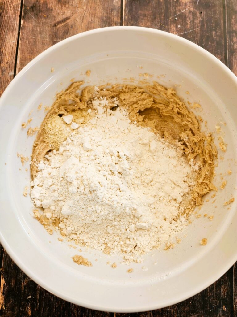 adding flour to almond cookie dough
