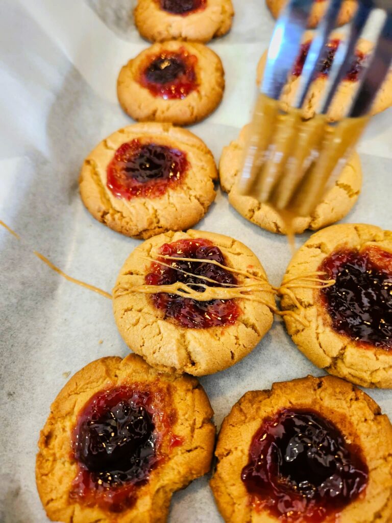 using a fork to drizzle warm peanut butter on cookies