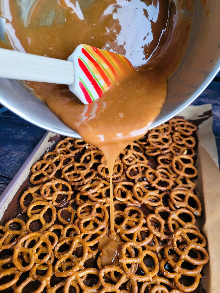 Drizzling smooth caramel melted in a double boiler over pretzels for five-layer chocolate peanut butter bars.