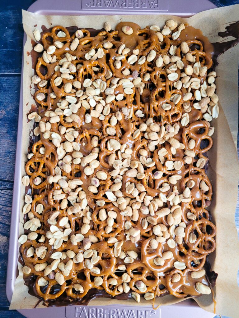 Adding dry roasted peanuts on top of caramel layer for soft and crunchy candy bar treats.