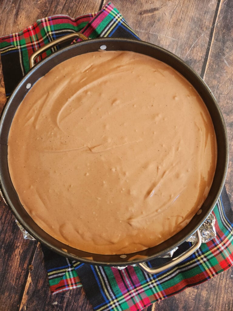 Chocolate cheesecake filling poured over cooled chocolate cookie crust in springform pan, ready for oven.