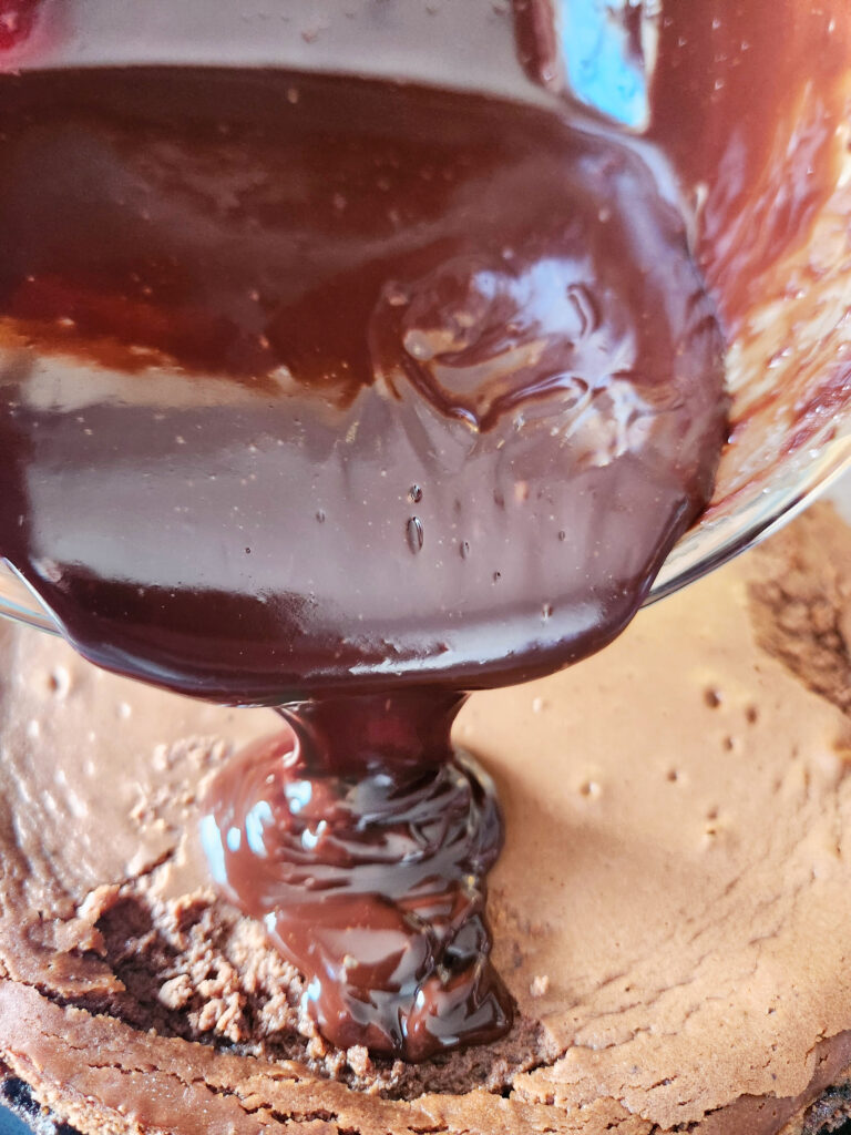 Smooth peppermint chocolate ganache being poured over chilled chocolate cheesecake for a glossy finish