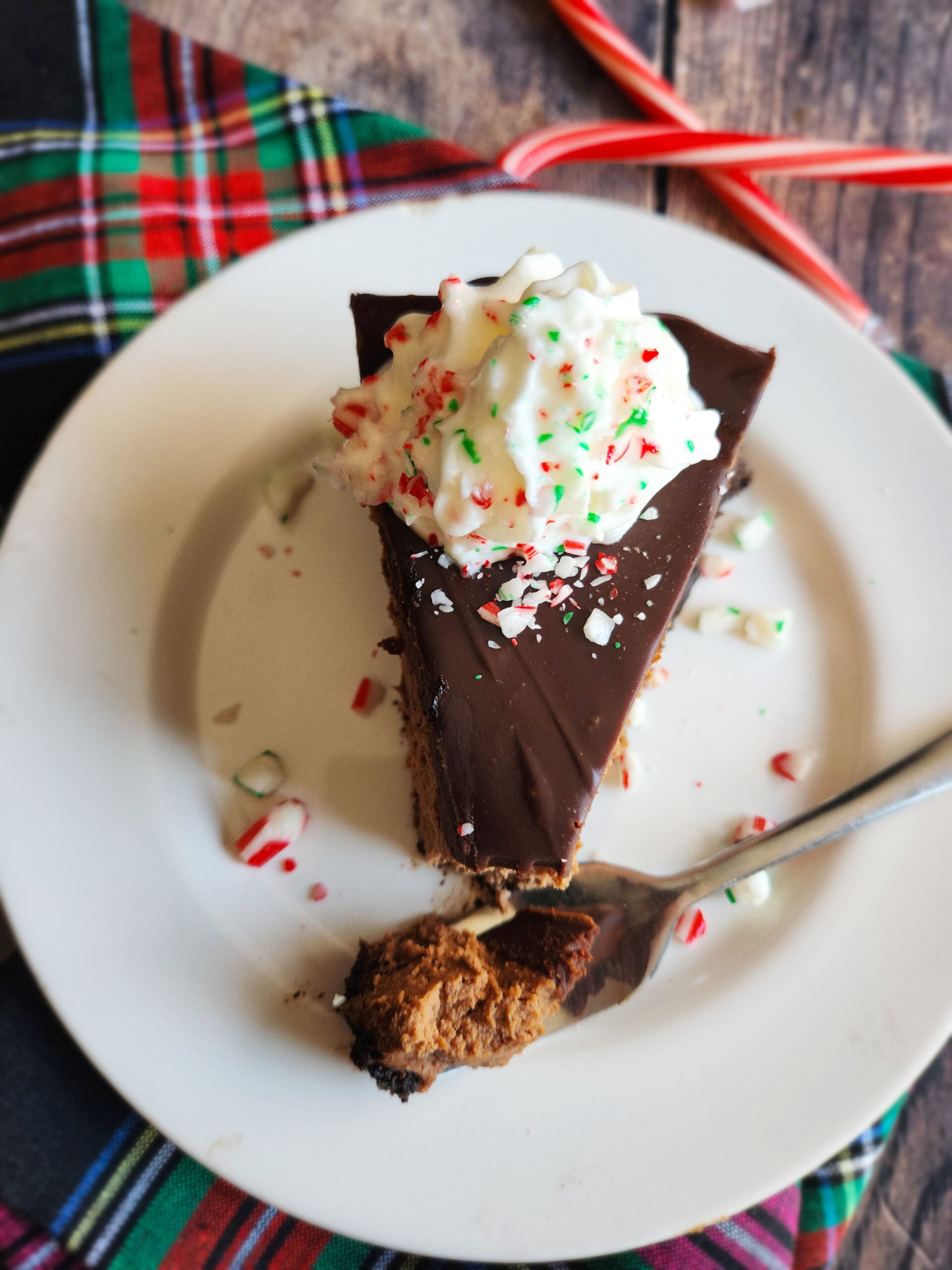 chocolate cheesecake with smooth peppermint mocha ganache, decorated with crushed candy canes, ready to serve.