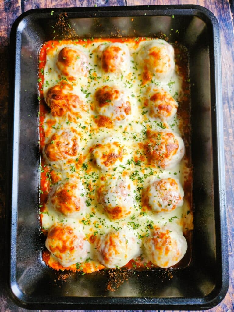 Chicken meatballs in tomato sauce under the broiler with mozzarella cheese bubbling and browning on top