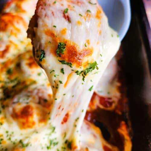 Close-up of juicy baked chicken meatballs coated in tomato sauce and melted mozzarella cheese with browned, bubbly top