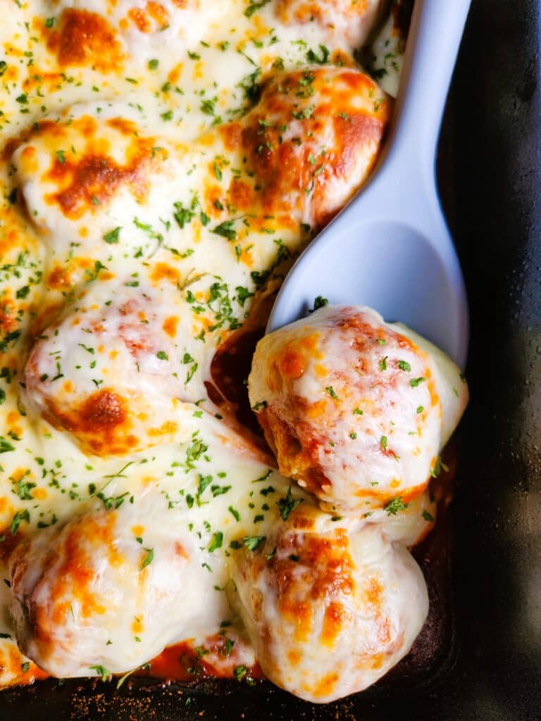 Baked chicken meatballs in tomato sauce topped with melted mozzarella cheese in a baking dish, perfect for pasta, meatball subs, or meal prep