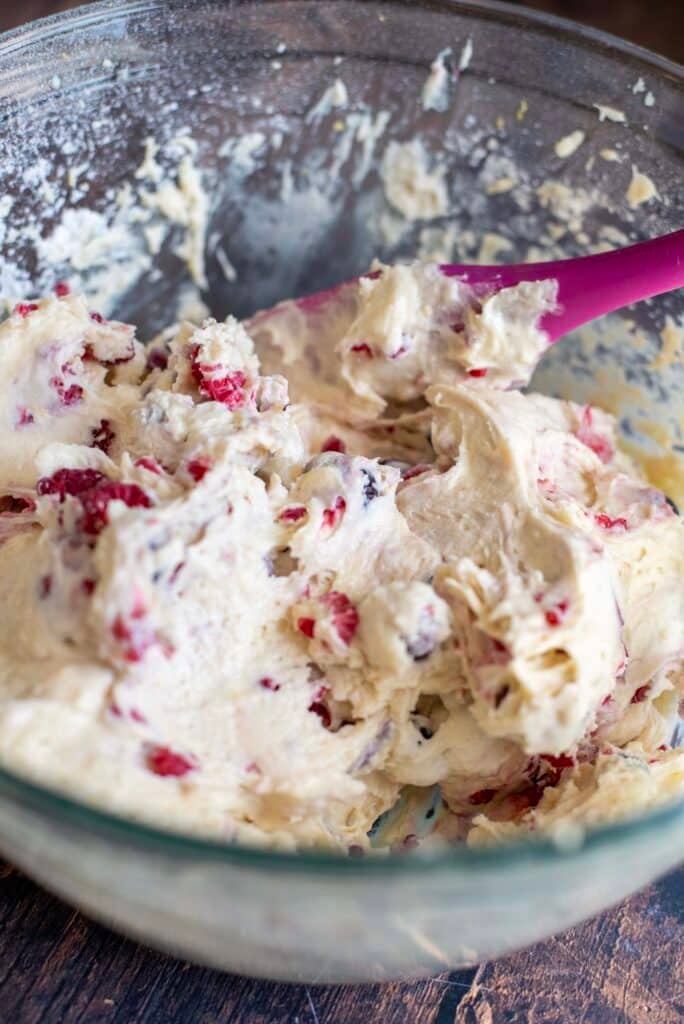 Frozen blueberries and raspberries being gently folded into lemon cake batter for berry skillet cake.