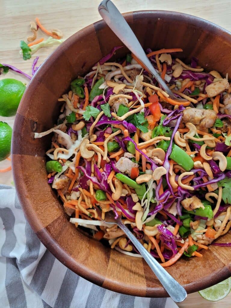 Large bowl of cashew crunch salad with sesame ginger dressing, chicken, colorful vegetables, cashews, and crispy chow mein noodles